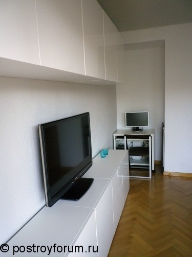 Белая гостиная с большим телевизором.