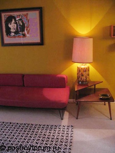 Уголок гостиной с розовым диваном и лампой.