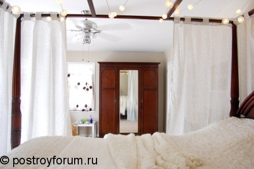 Белая спальная кровать со шторами.
